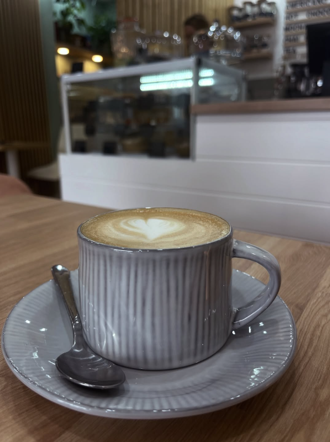 Latte with heart latte art in a ribbed cup on a saucer at Cristina's Cafe Romford